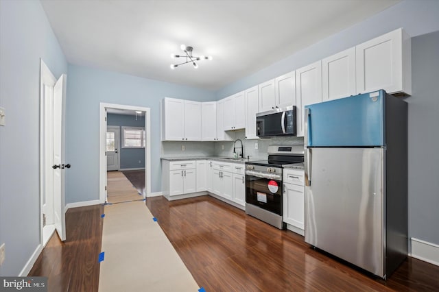 kitchen featuring a sink, tasteful backsplash, dark wood finished floors, white cabinetry, and appliances with stainless steel finishes