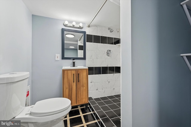 bathroom featuring vanity, toilet, and tiled shower