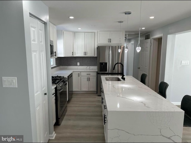 kitchen featuring a sink, a kitchen island with sink, visible vents, light wood finished floors, and range with gas stovetop
