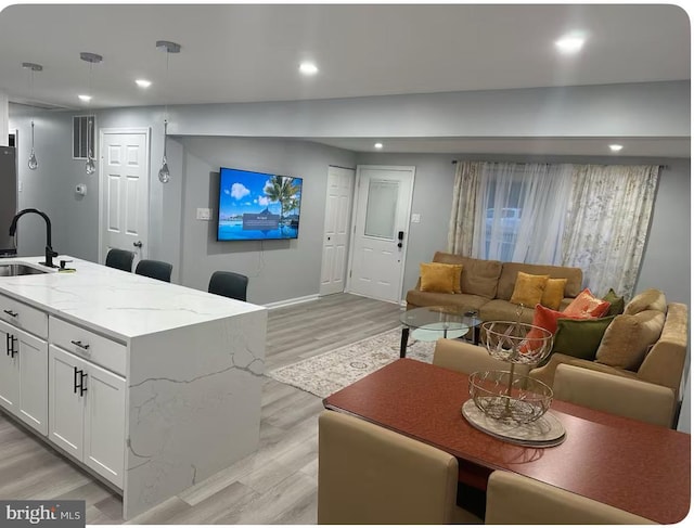 living room featuring light wood-style flooring, baseboards, and recessed lighting