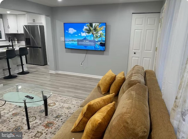 living area featuring baseboards, light wood-style floors, and recessed lighting