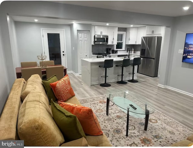 living area featuring light wood finished floors, baseboards, and recessed lighting