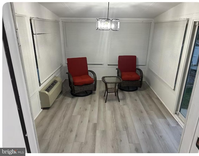 sitting room with vaulted ceiling, an inviting chandelier, a wall mounted air conditioner, and wood finished floors