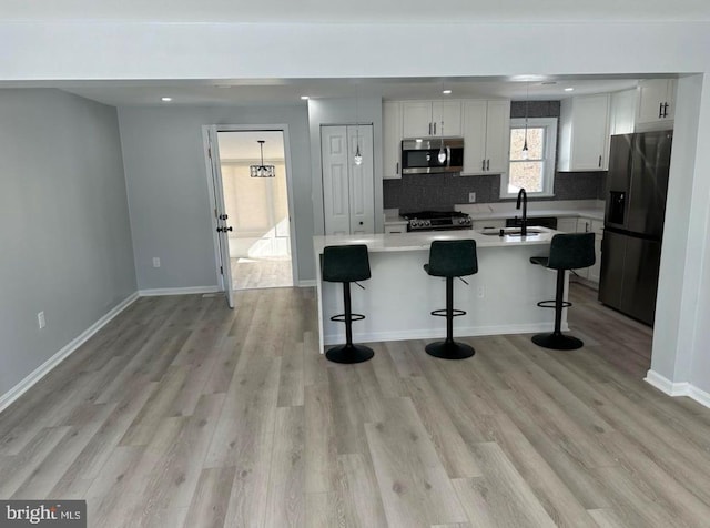 kitchen with gas range oven, black fridge, a sink, stainless steel microwave, and white cabinets
