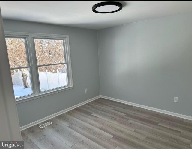 spare room with visible vents, wood finished floors, and baseboards