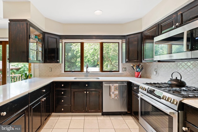 kitchen with appliances with stainless steel finishes, a sink, light countertops, and light tile patterned floors