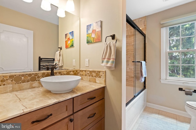 bathroom featuring plenty of natural light, decorative backsplash, vanity, and toilet
