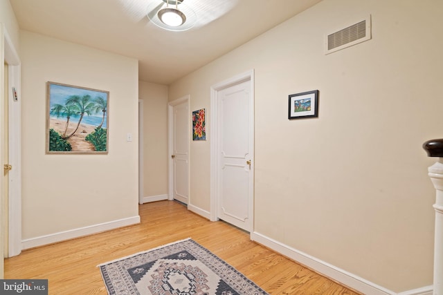 corridor featuring light wood-type flooring and baseboards