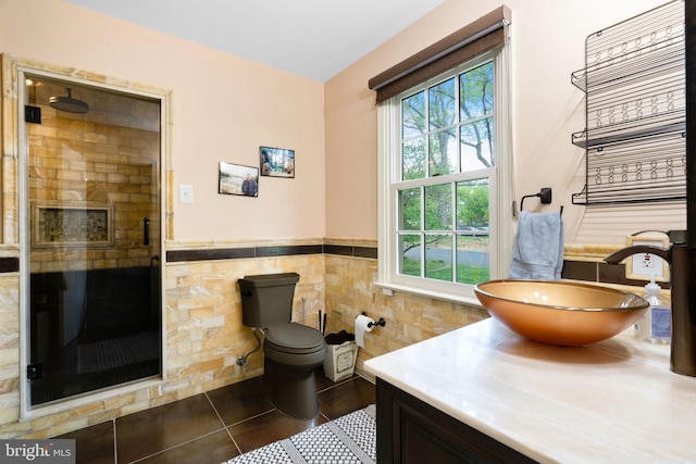bathroom featuring a stall shower, vanity, healthy amount of natural light, a wainscoted wall, and toilet
