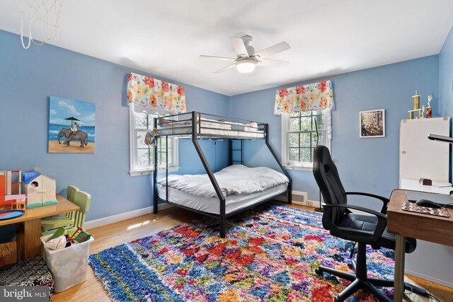 bedroom with wood finished floors, baseboards, an office area, and ceiling fan