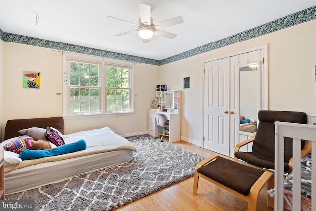 bedroom with wood finished floors, baseboards, a ceiling fan, and a closet