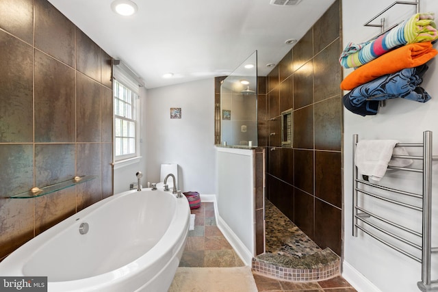 full bath with a tub, a walk in shower, recessed lighting, radiator heating unit, and stone finish flooring