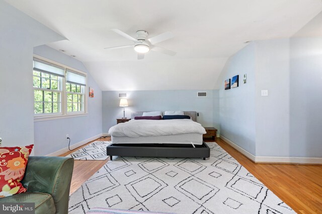 bedroom featuring baseboards, light wood finished floors, vaulted ceiling, and a ceiling fan