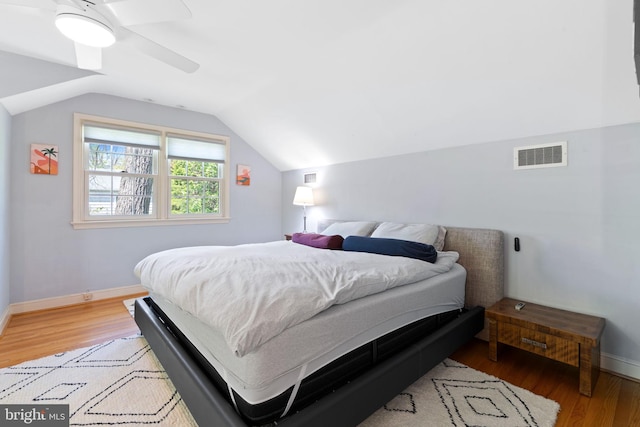 bedroom featuring light wood finished floors, lofted ceiling, baseboards, and ceiling fan