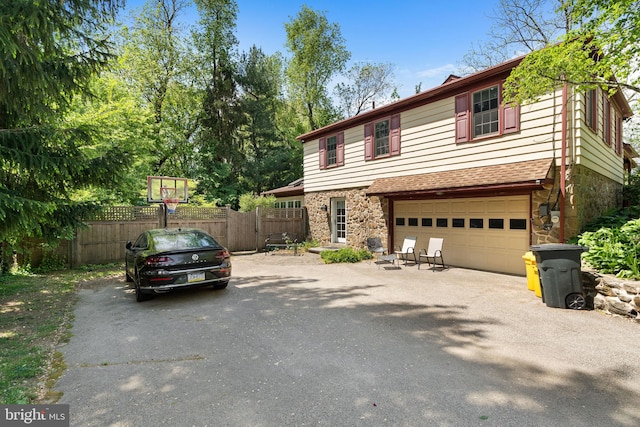 view of front of property with asphalt driveway, stone siding, and fence