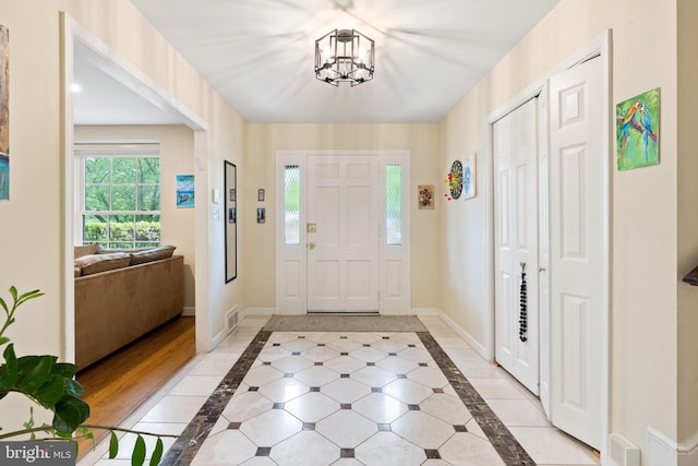 entrance foyer featuring inlaid floor details, a chandelier, and baseboards