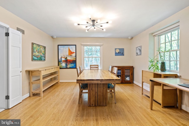 dining space featuring light wood finished floors, baseboards, and a chandelier