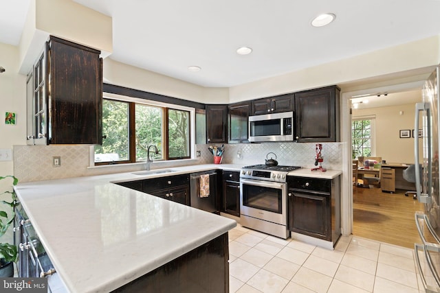 kitchen featuring appliances with stainless steel finishes, a sink, light countertops, light tile patterned floors, and dark brown cabinets
