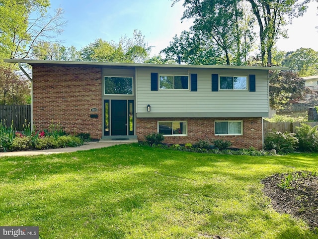 view of front facade featuring brick siding, a front lawn, and fence