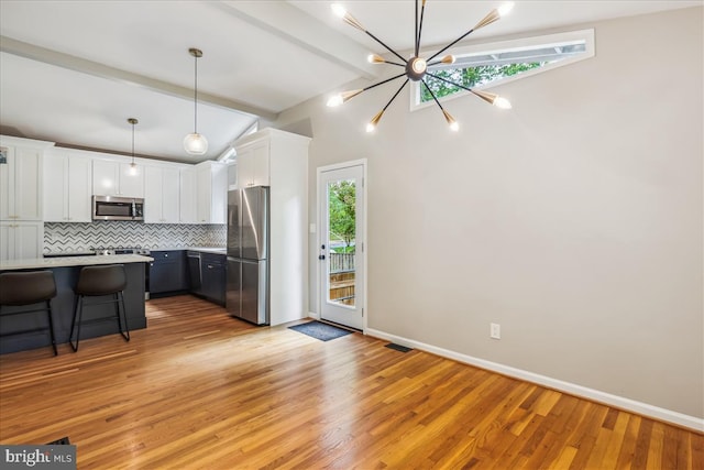 kitchen with backsplash, lofted ceiling with beams, plenty of natural light, and appliances with stainless steel finishes