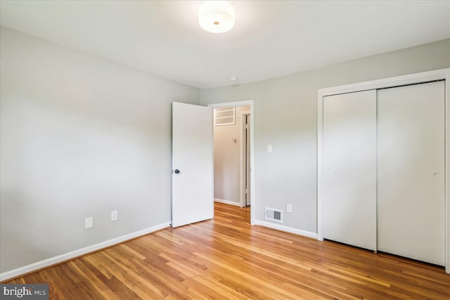unfurnished bedroom featuring light wood finished floors, baseboards, a closet, and visible vents