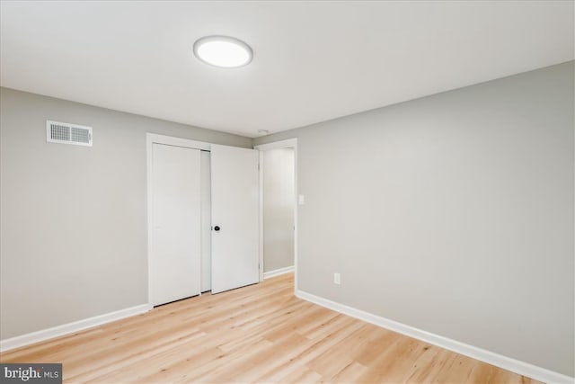 unfurnished bedroom featuring a closet, light wood-style floors, visible vents, and baseboards