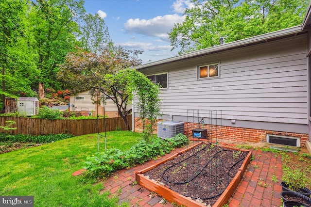 view of yard featuring a vegetable garden, central AC unit, and fence