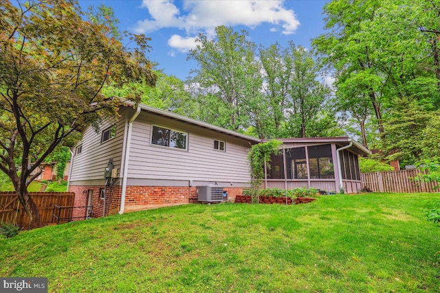 rear view of property with a lawn, central AC, a sunroom, and a fenced backyard