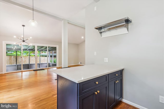 kitchen featuring a chandelier, open floor plan, light countertops, hanging light fixtures, and light wood-style floors