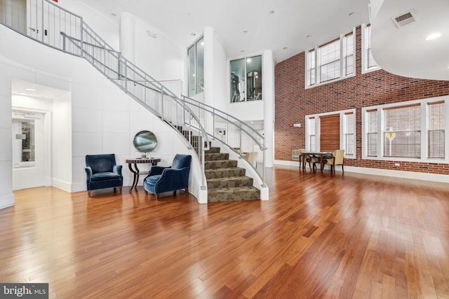 23 Arch Pl Unit 475, Gaithersburg, MD 20878 - living area with a high ceiling, stairs, hardwood / wood-style flooring, brick wall, and baseboards