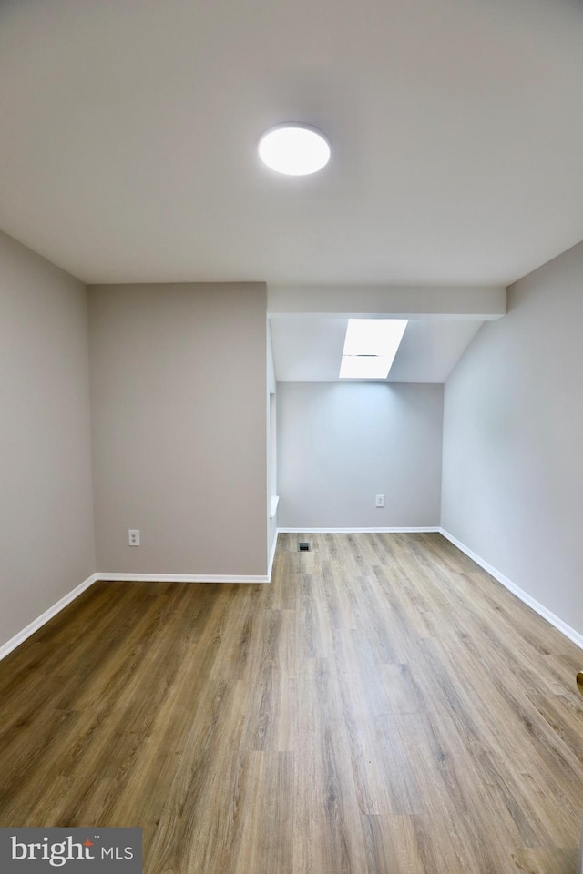 bonus room featuring lofted ceiling with skylight, baseboards, visible vents, and wood finished floors