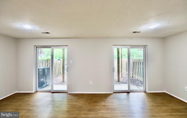 spare room featuring visible vents, plenty of natural light, and wood finished floors