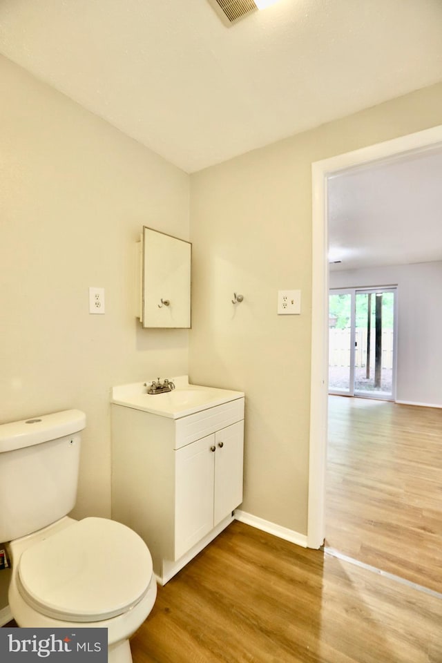 bathroom featuring vanity, toilet, wood finished floors, and baseboards