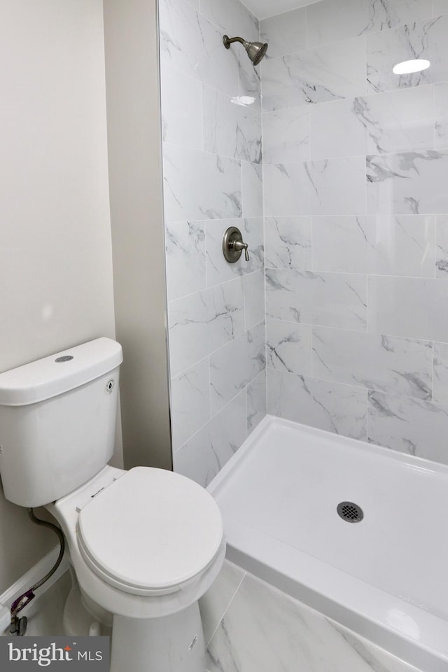 bathroom featuring toilet, a shower stall, and marble finish floor
