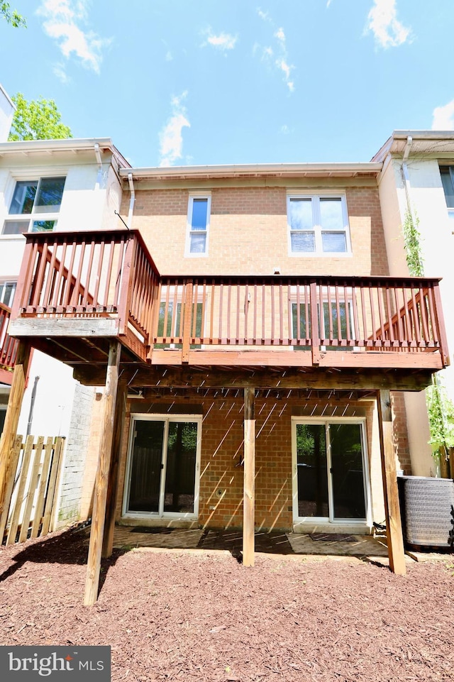 rear view of property featuring a deck and brick siding