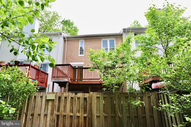 back of house with fence, brick siding, and a deck