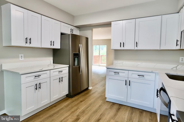 kitchen with dishwashing machine, stainless steel fridge, white cabinets, light stone countertops, and light wood-style floors