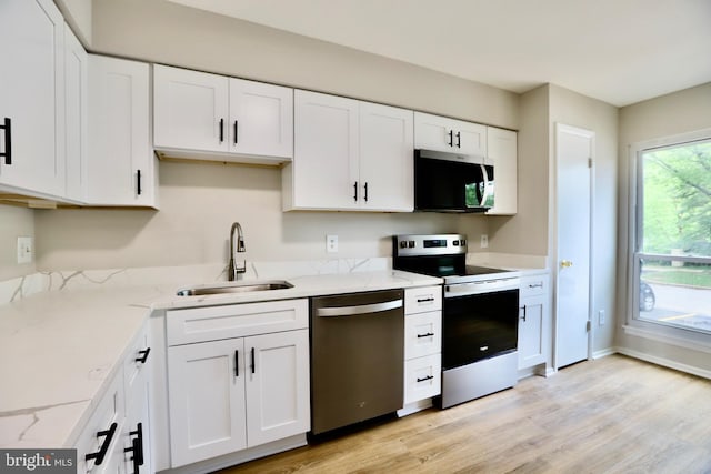 kitchen featuring a sink, white cabinetry, light stone counters, and appliances with stainless steel finishes