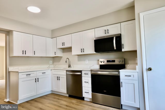 kitchen featuring white cabinetry, light wood finished floors, stainless steel appliances, and a sink