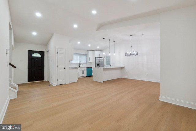 7813 Main Falls Cir, Baltimore, MD 21228 - unfurnished living room with a sink, vaulted ceiling, baseboards, a chandelier, and light wood-style floors