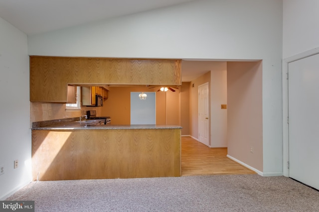 10703 Moray Ct, Cheltenham, MD 20623 - kitchen with a peninsula, light colored carpet, stainless steel gas range oven, vaulted ceiling, and a sink