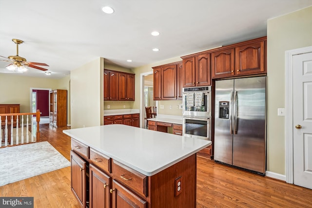 12630 Garry Glen Dr, Bristow, VA 20136 - kitchen featuring appliances with stainless steel finishes, a center island, light countertops, light wood finished floors, and ceiling fan
