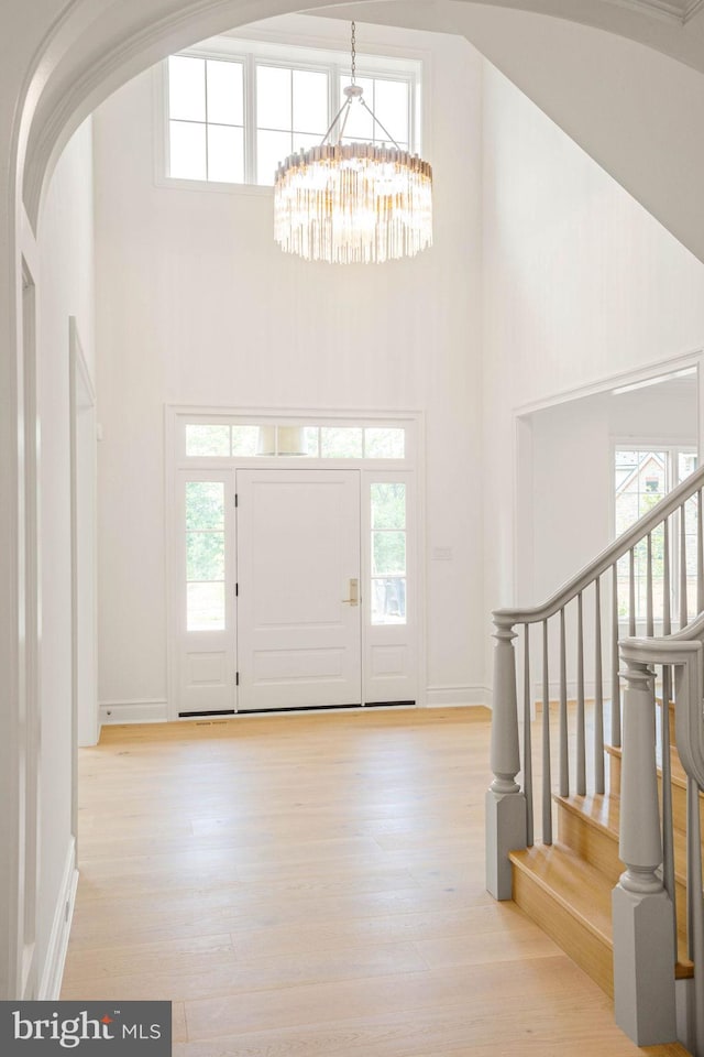 entryway featuring a high ceiling, a chandelier, healthy amount of natural light, and light wood-style floors