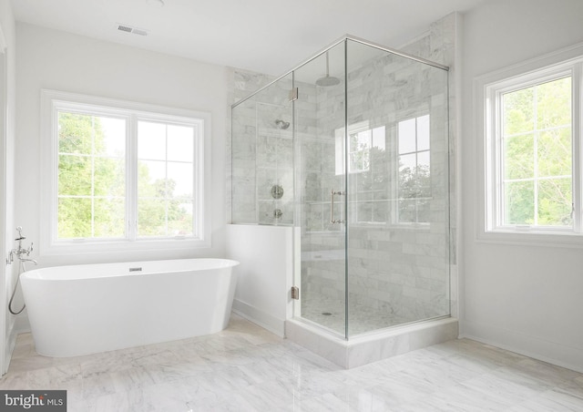 full bath featuring a stall shower, a freestanding tub, and marble finish flooring