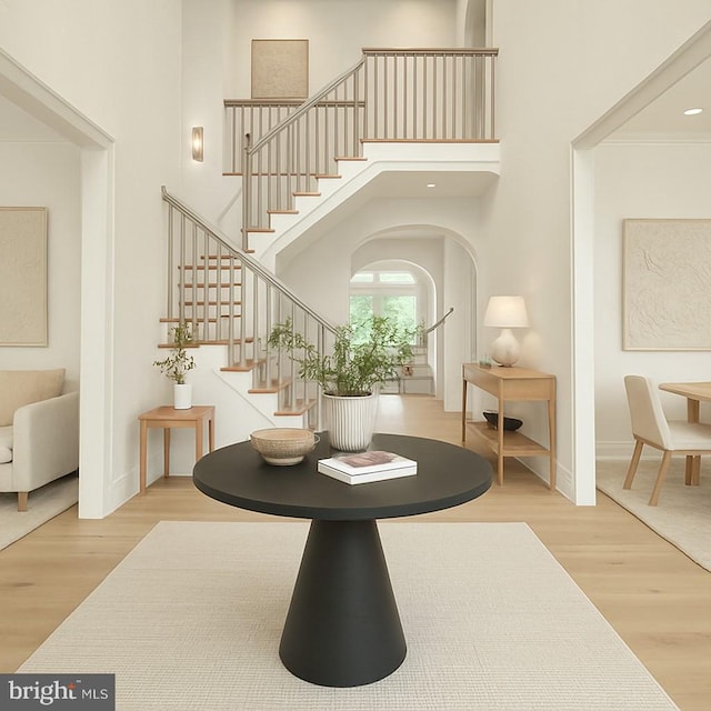 foyer featuring stairway, wood finished floors, a high ceiling, arched walkways, and baseboards