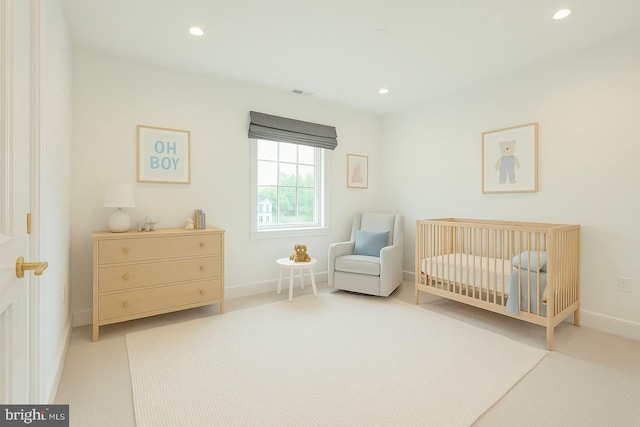 bedroom with recessed lighting, a crib, baseboards, and light carpet