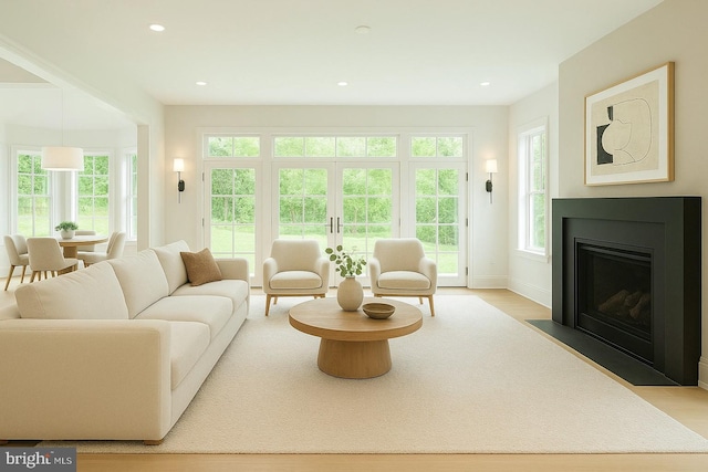 living area with a fireplace with flush hearth, light wood finished floors, baseboards, and recessed lighting