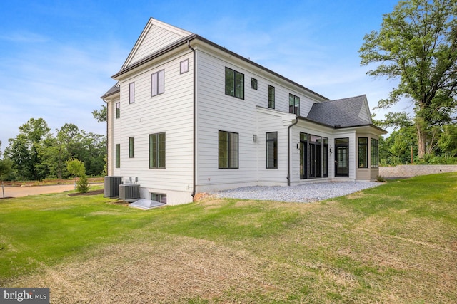 rear view of property featuring a lawn and cooling unit