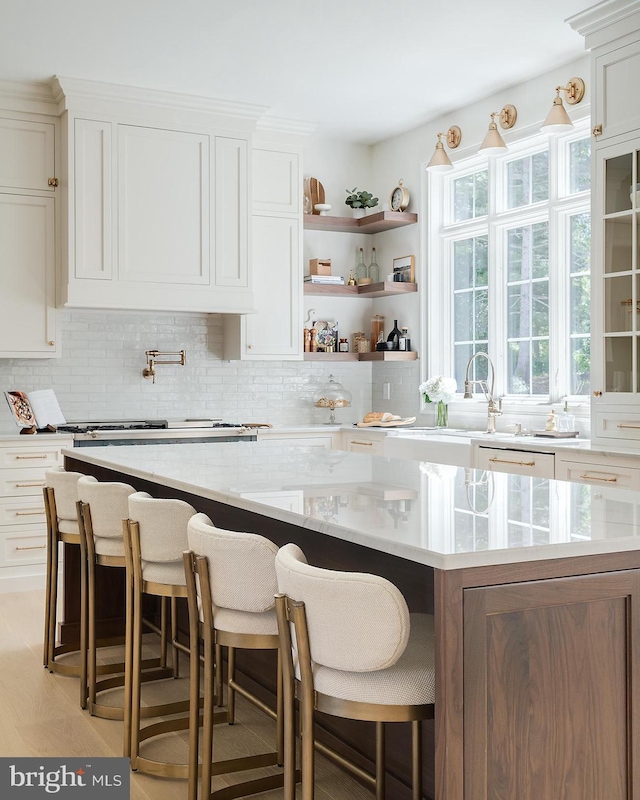 kitchen with a kitchen island, decorative backsplash, white cabinets, and light stone countertops