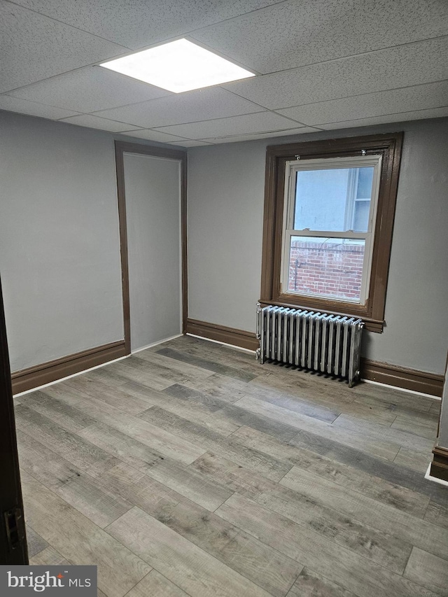 unfurnished room with radiator heating unit, wood finished floors, and baseboards